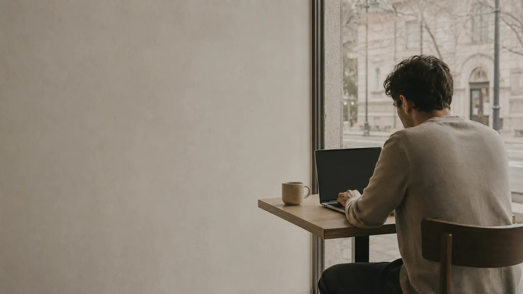 A freelancer working on a laptop in a sunlit café